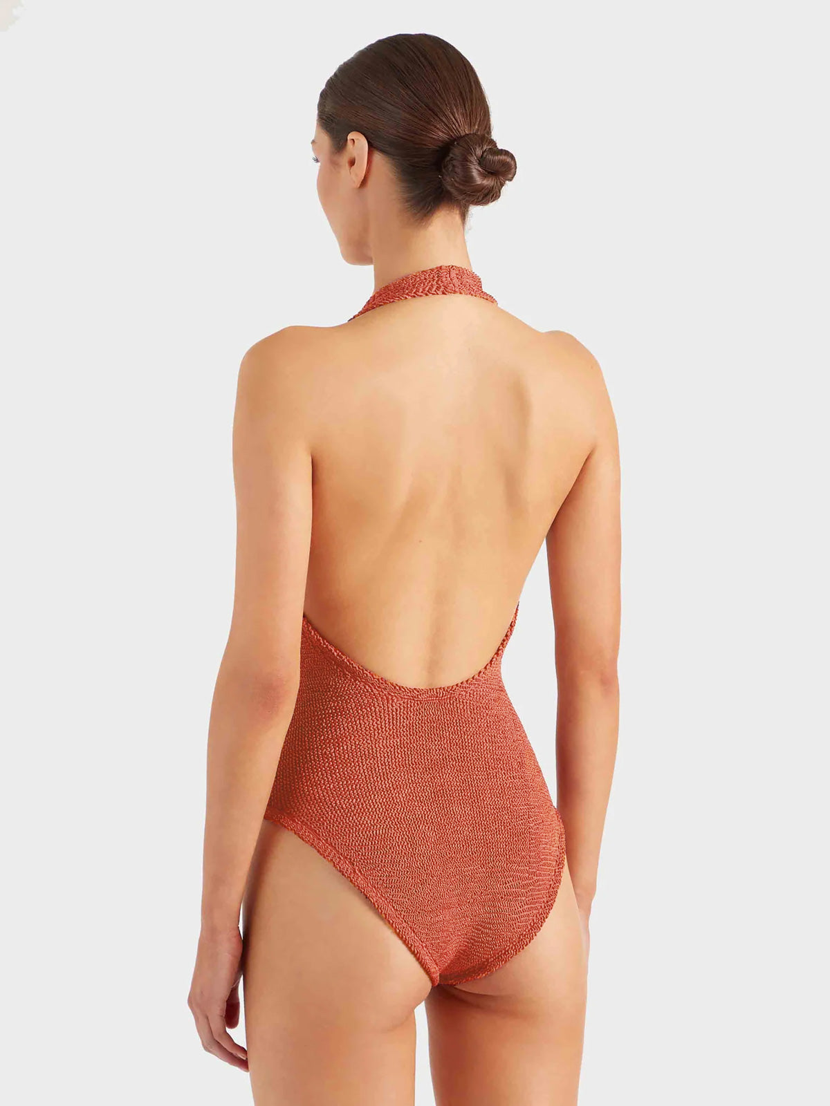 Back of model wearing deep orange halterneck swimsuit