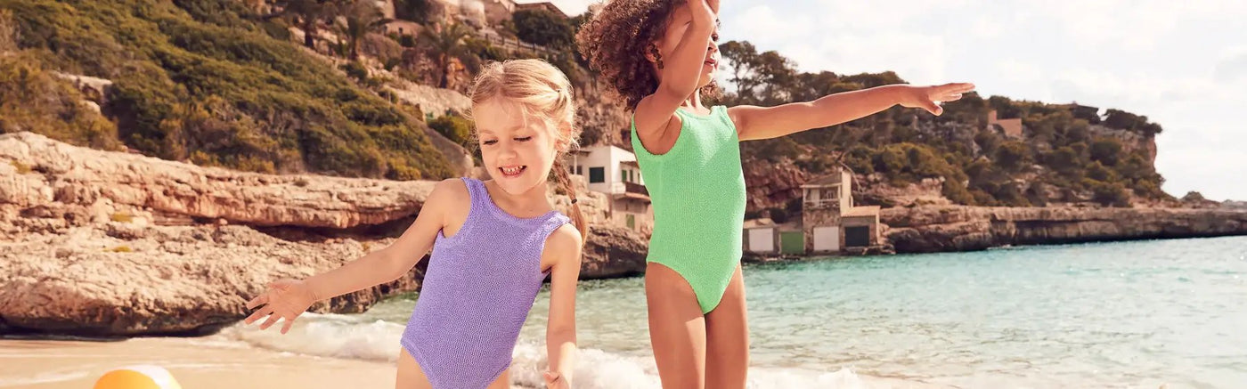 toddlers wearing swimsuits playing in water