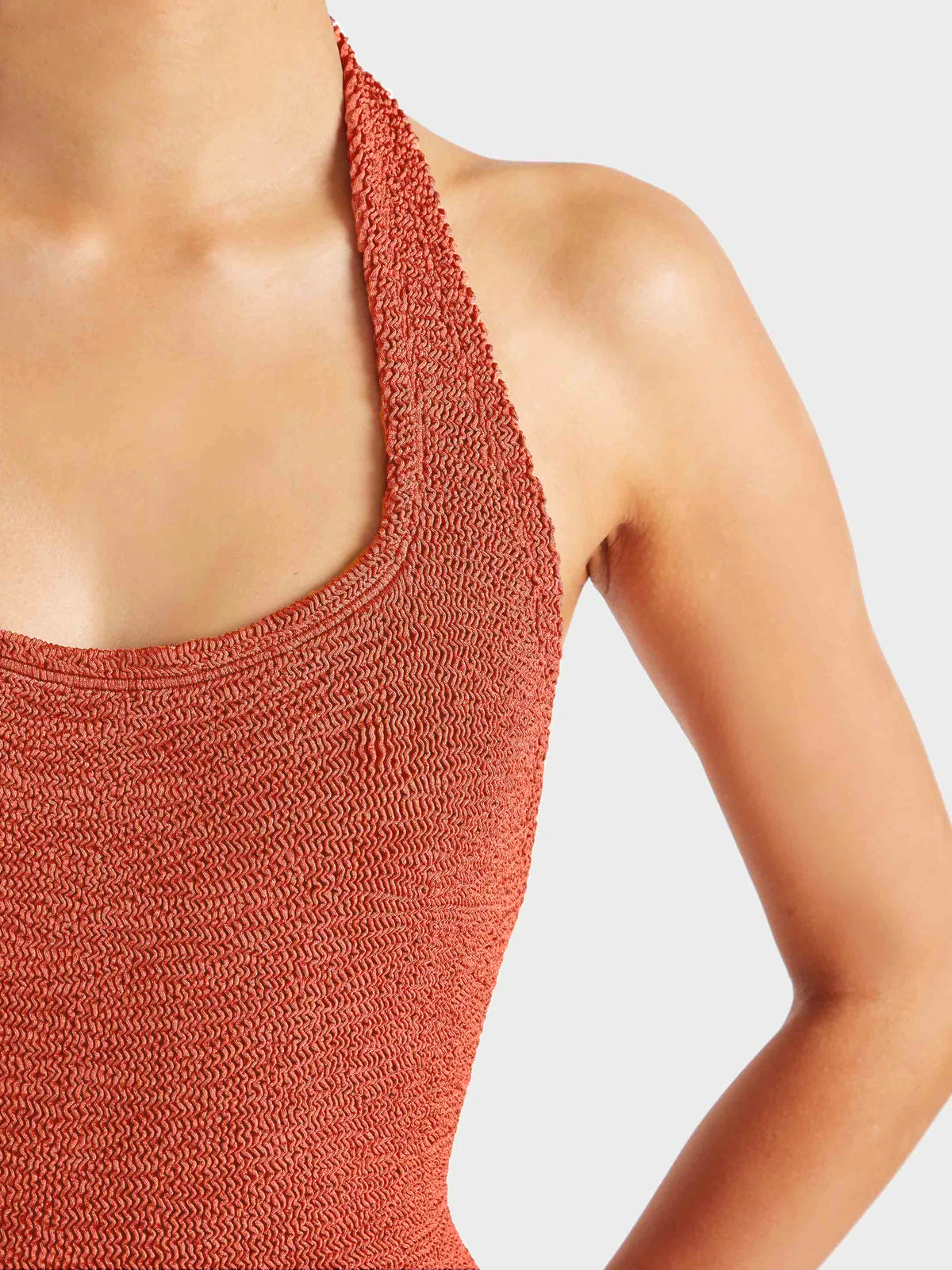 Close up of model wearing deep orange halterneck swimsuit
